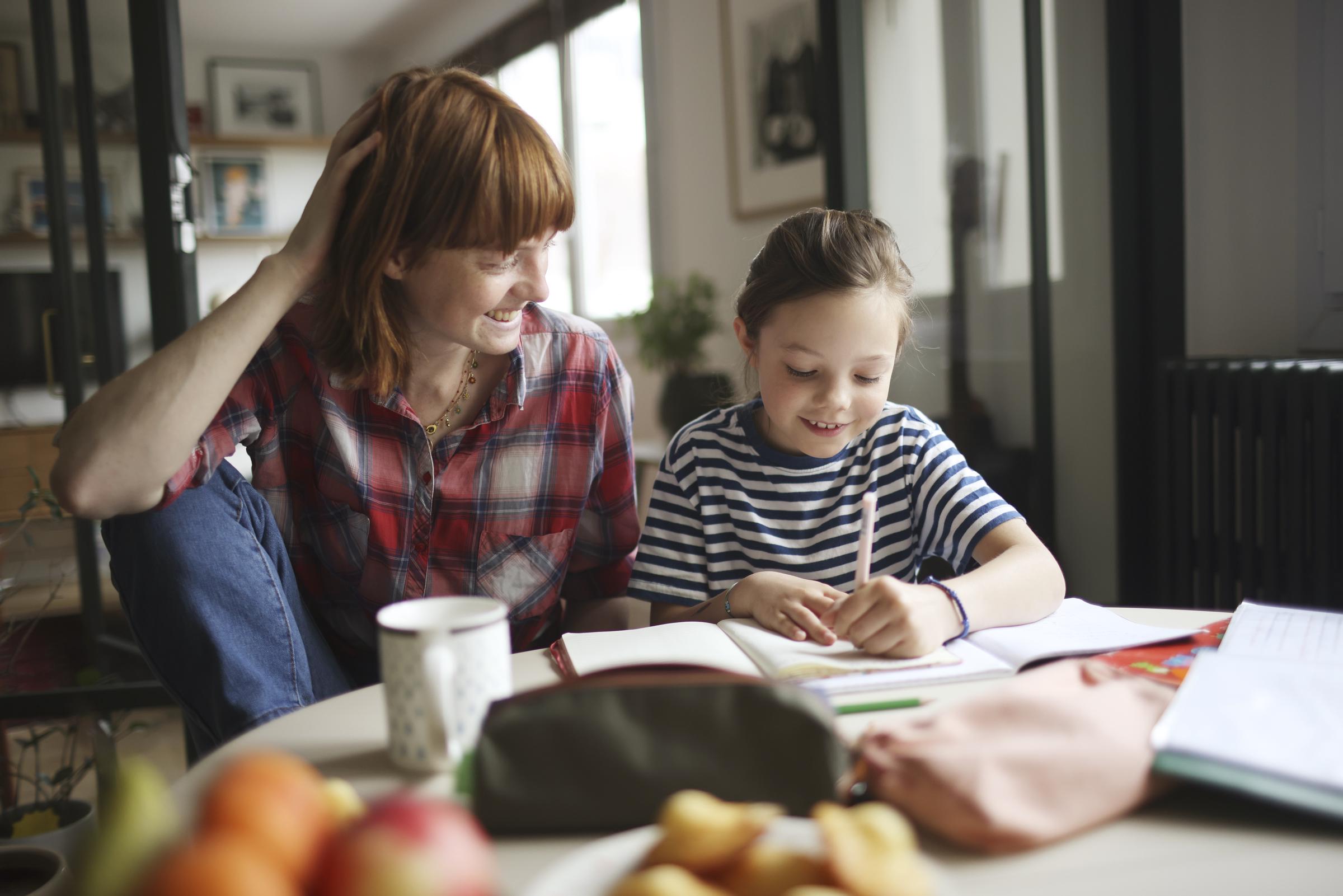 A girl and her mom doing homework at home | Source: Getty Images