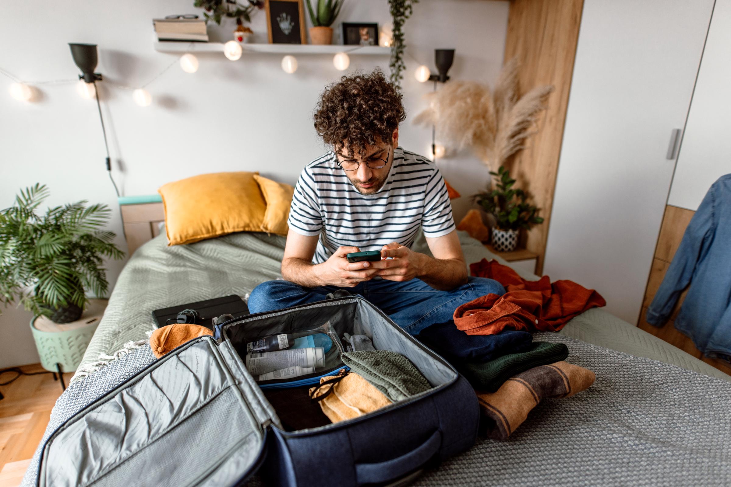 A man sitting in his bedroom, preparing for a trip | Source: Getty Images