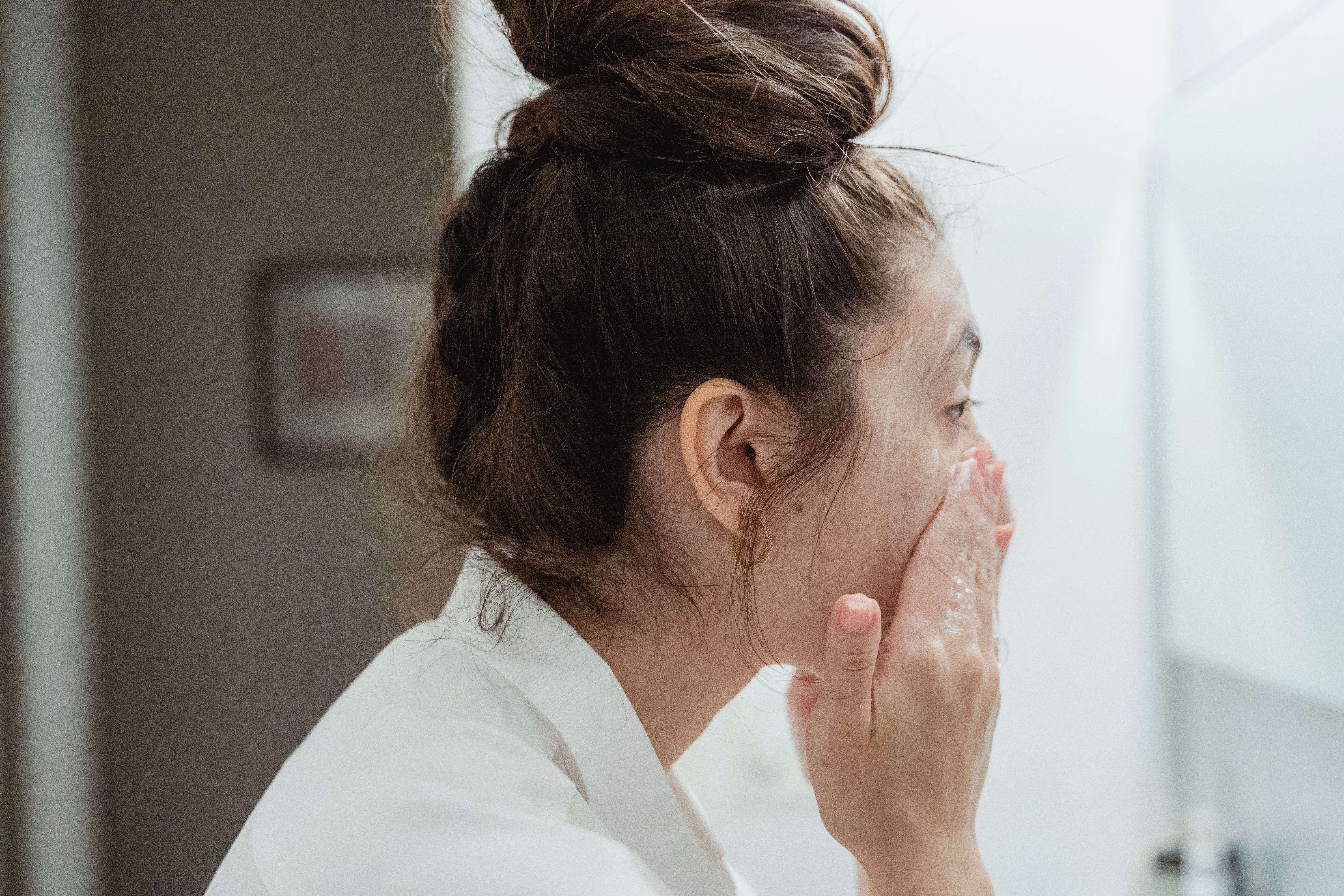 Woman washing her face with a cleanser | Source: Pexels