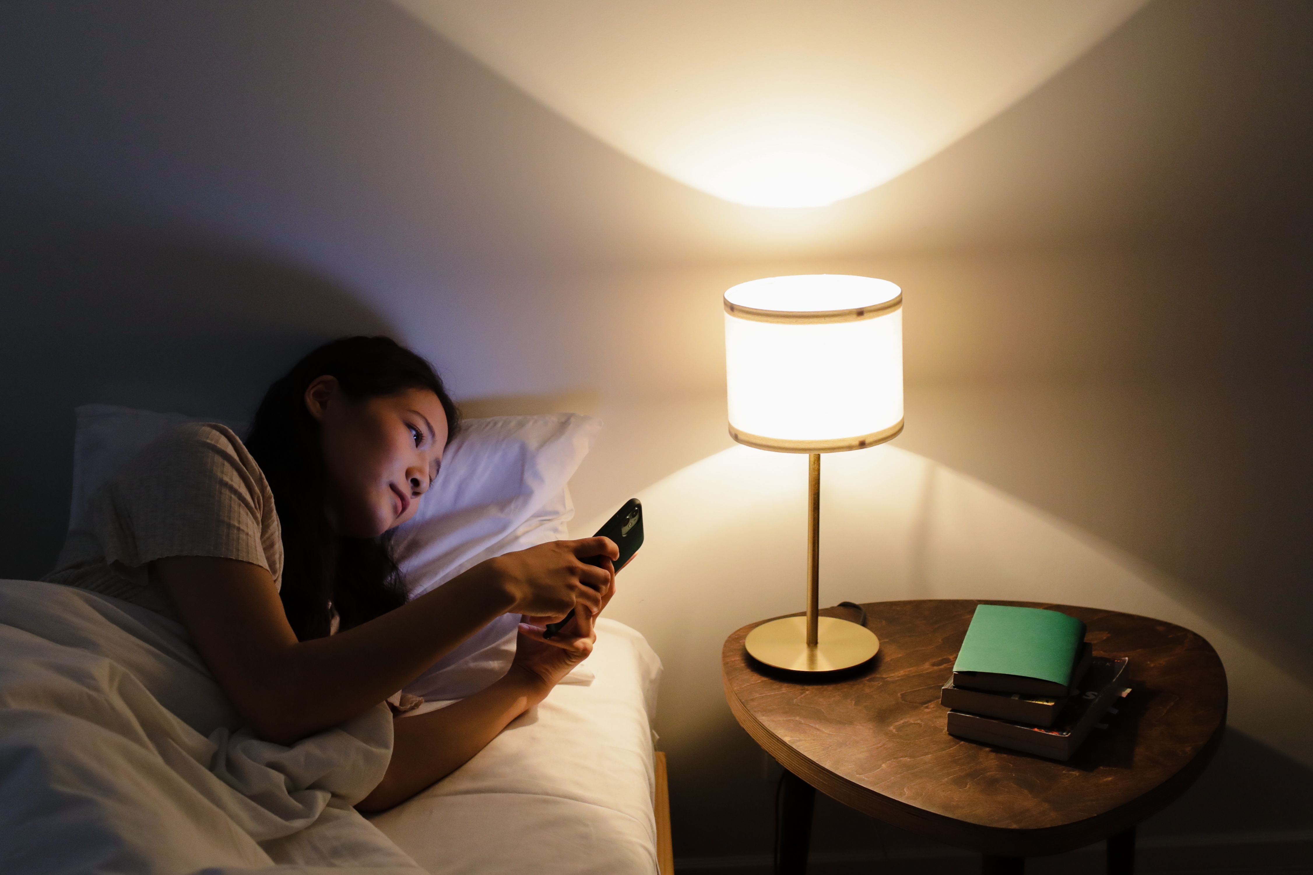A woman looking at her phone while in bed | Source: Pexels