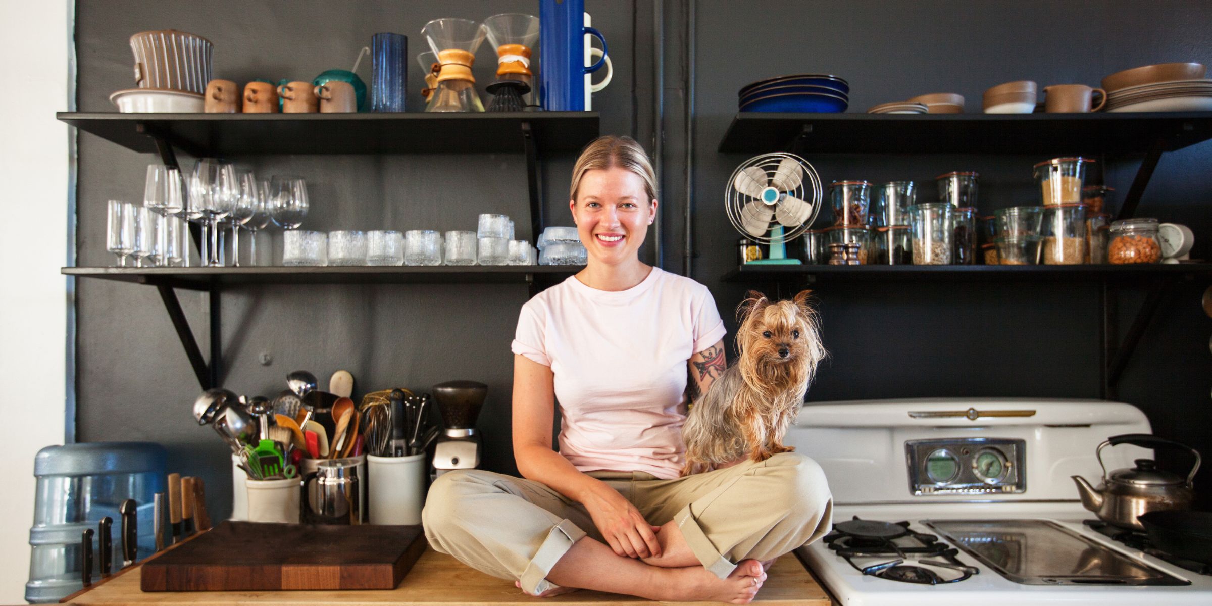 A woman sitting cross-legged on her kitchen counter with her dog | Source: Getty Images