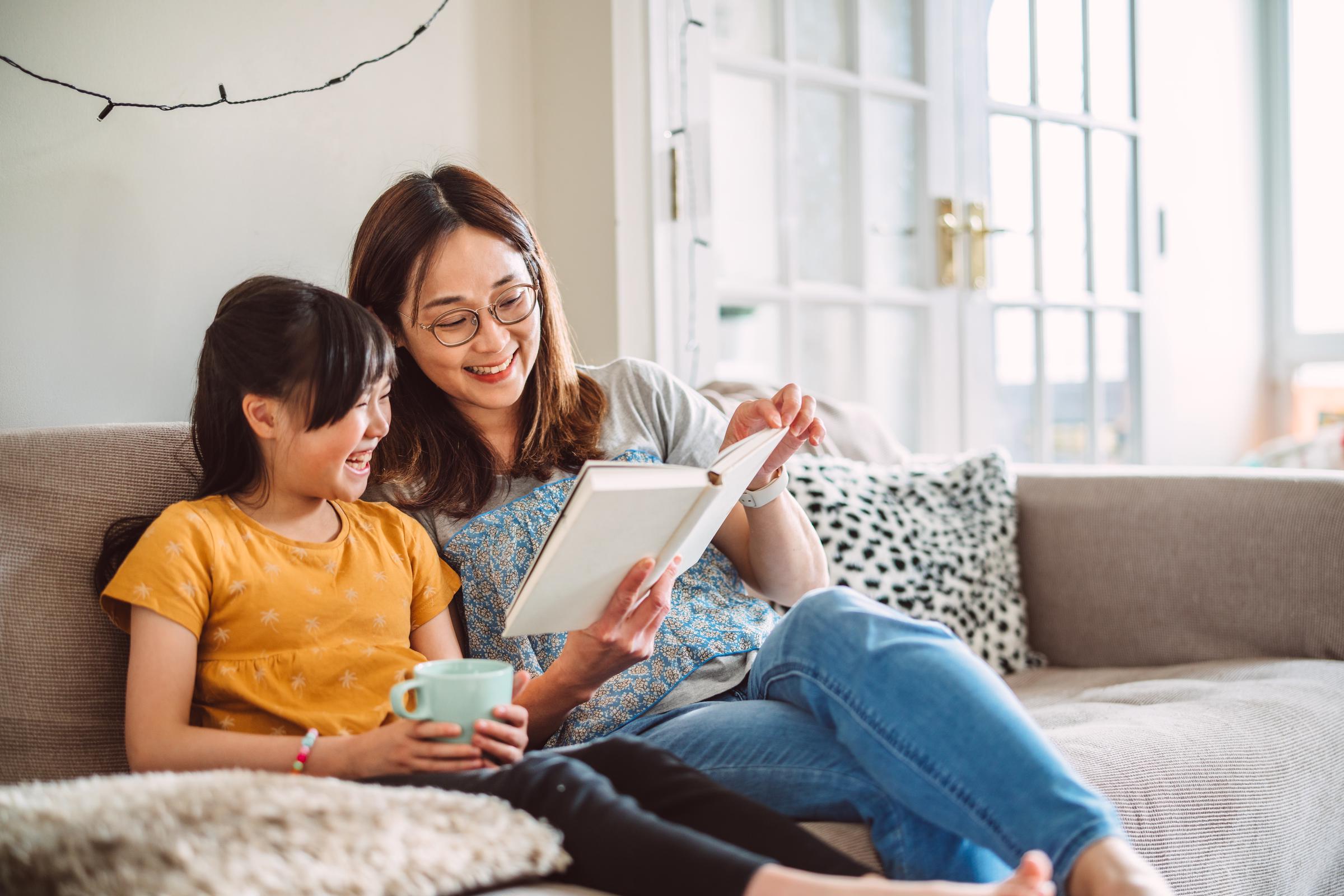 A mother and daughter relaxing on the sofa while reading a book together | Source: Getty Images