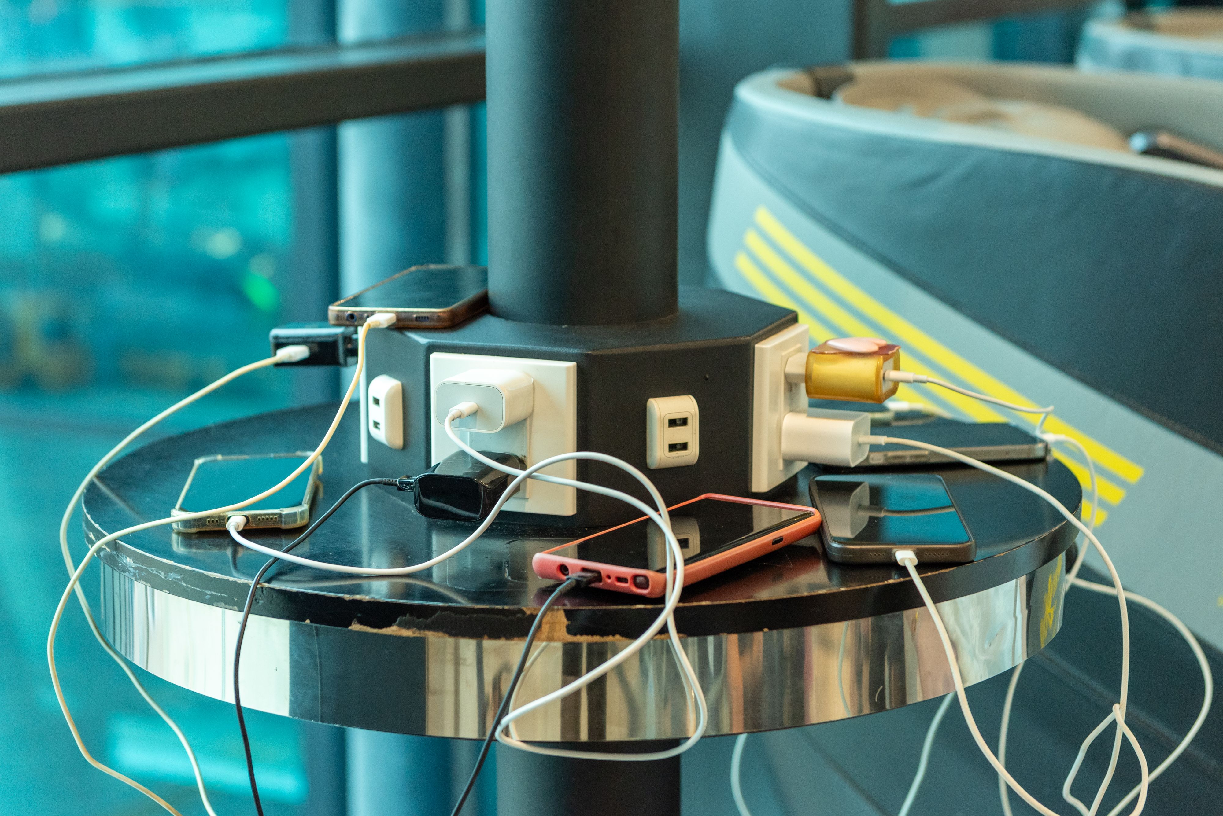 Several phones charge on a round table around a column with built-in outlets and USB ports. | Source: Pexels