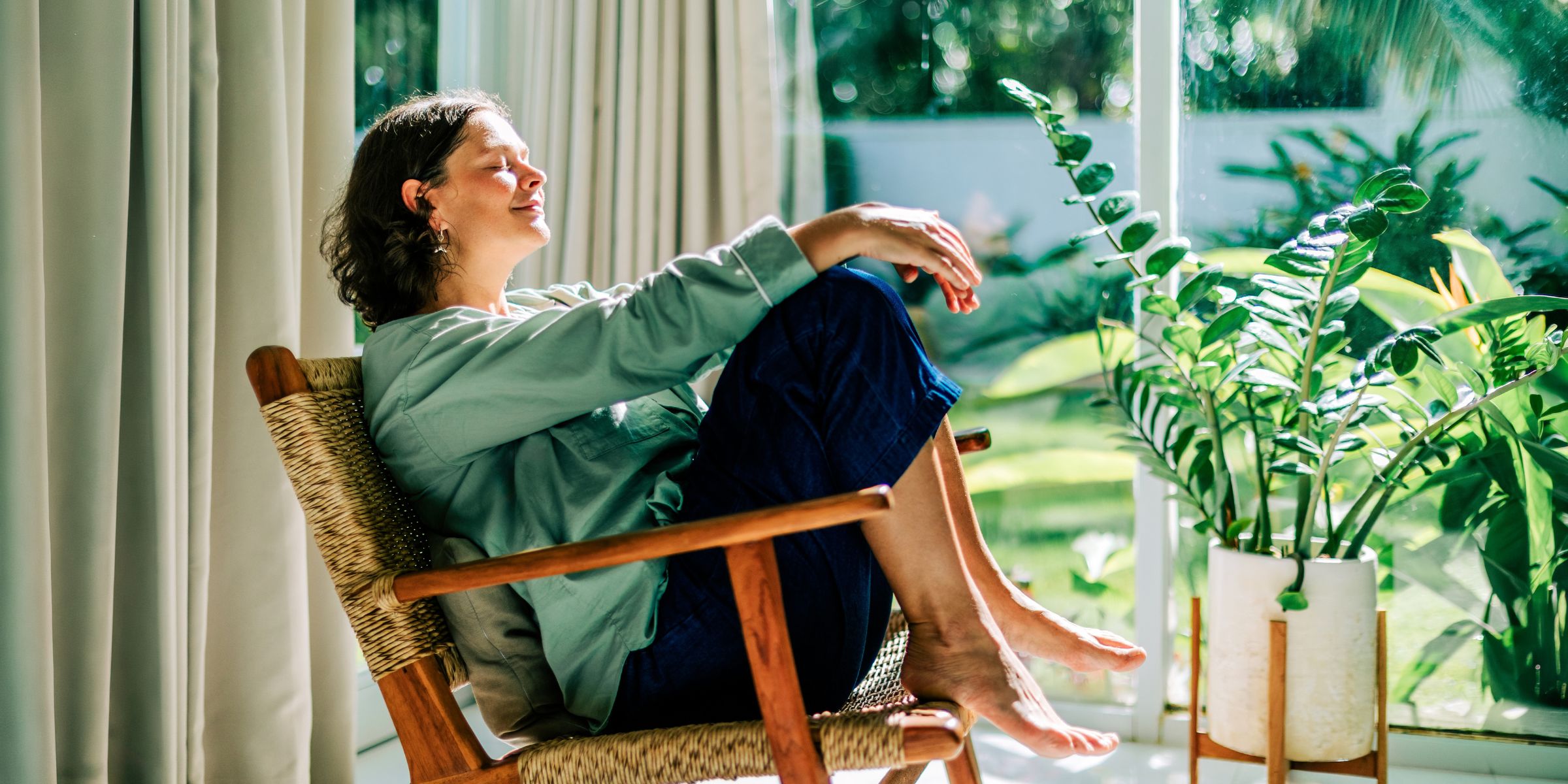 A woman relaxing in an armchair by the window, enjoying the morning sun | Source: Getty Images