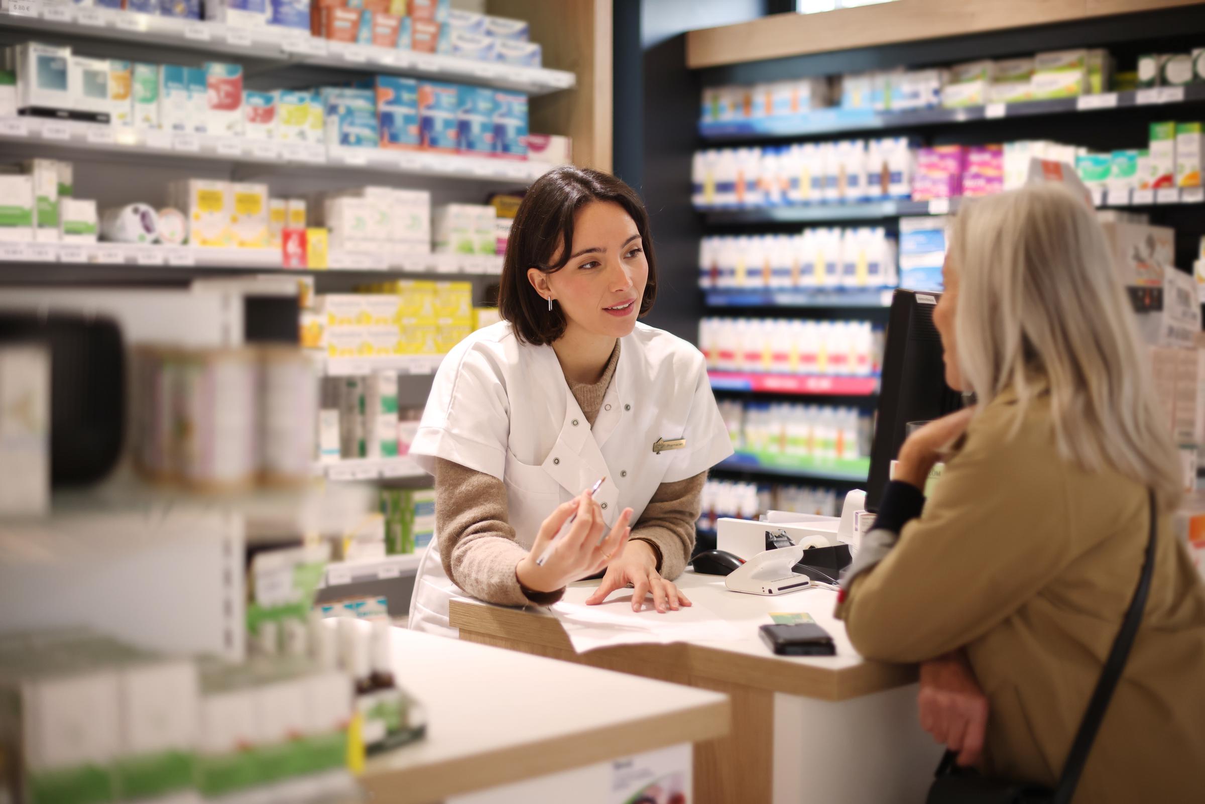 A pharmacist giving recommendations to a senior customer at a pharmacy counter | Source: Getty Images