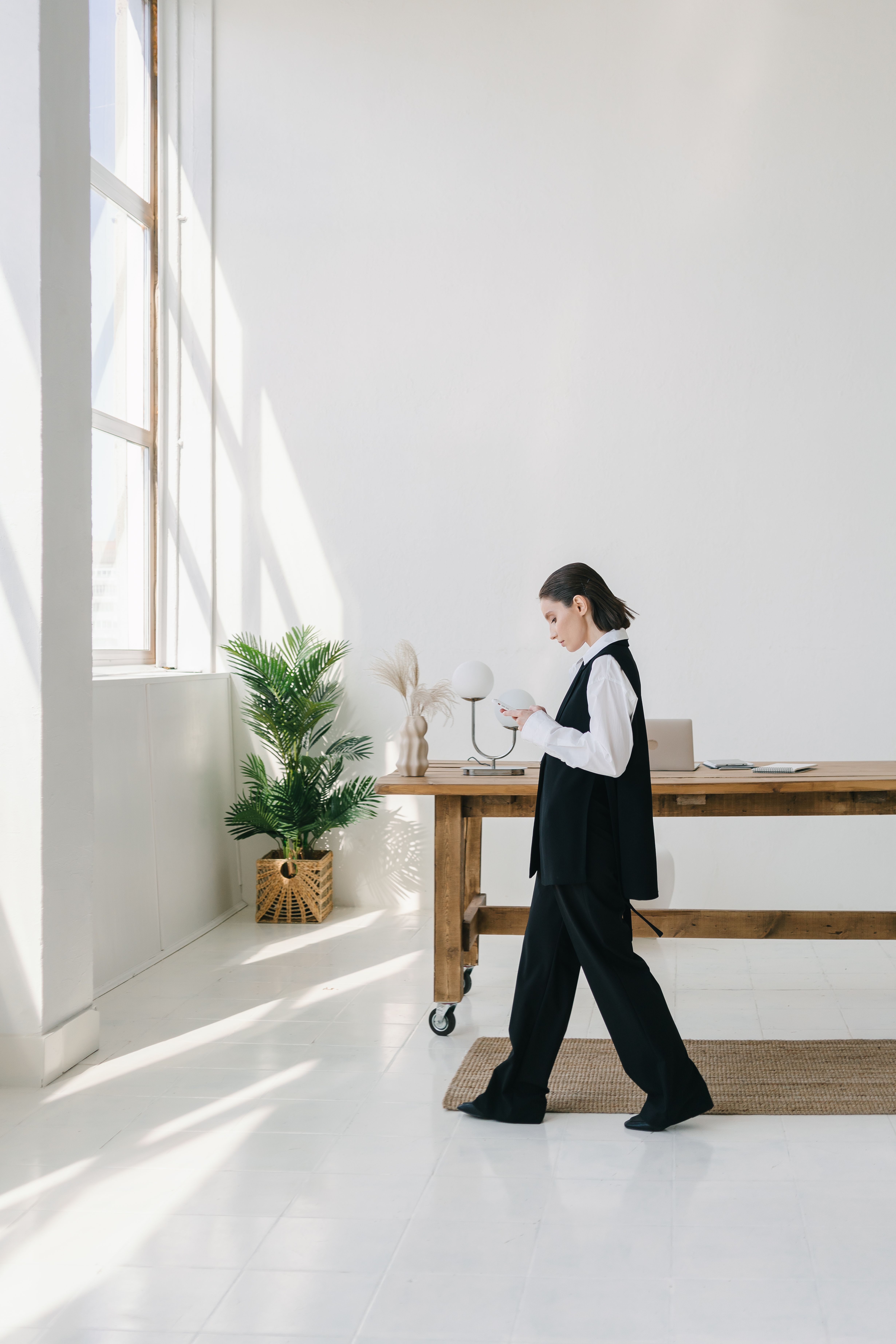 A woman walking inside an office while looking at her phone | Source: Pexels