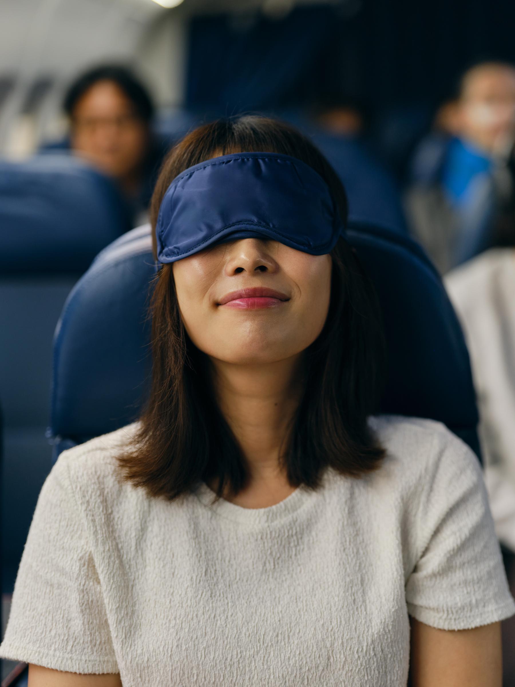 A woman resting with a sleep mask in a plane | Source: Getty Images