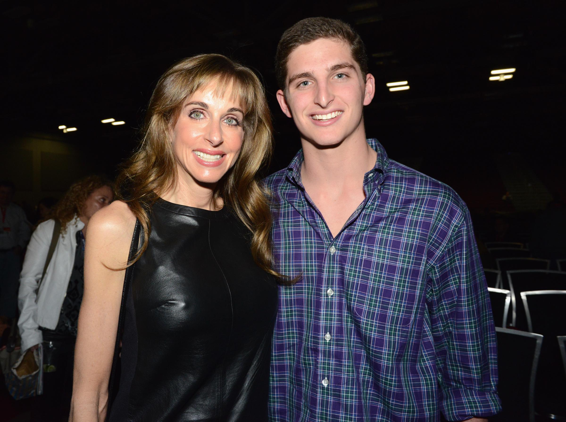 Susan Dell and her son, Zack Dell, smile warmly while posing together at the Michael Dell Session during the 2014 SXSW Music, Film + Interactive Festival at the Austin Convention Center on March 7, 2014, in Austin, Texas. Susan wears a sleeveless black leather top with her hair styled in soft waves and fringe bangs, while Zack stands beside her in a casual blue and green plaid button-down shirt. | Source: Getty Images