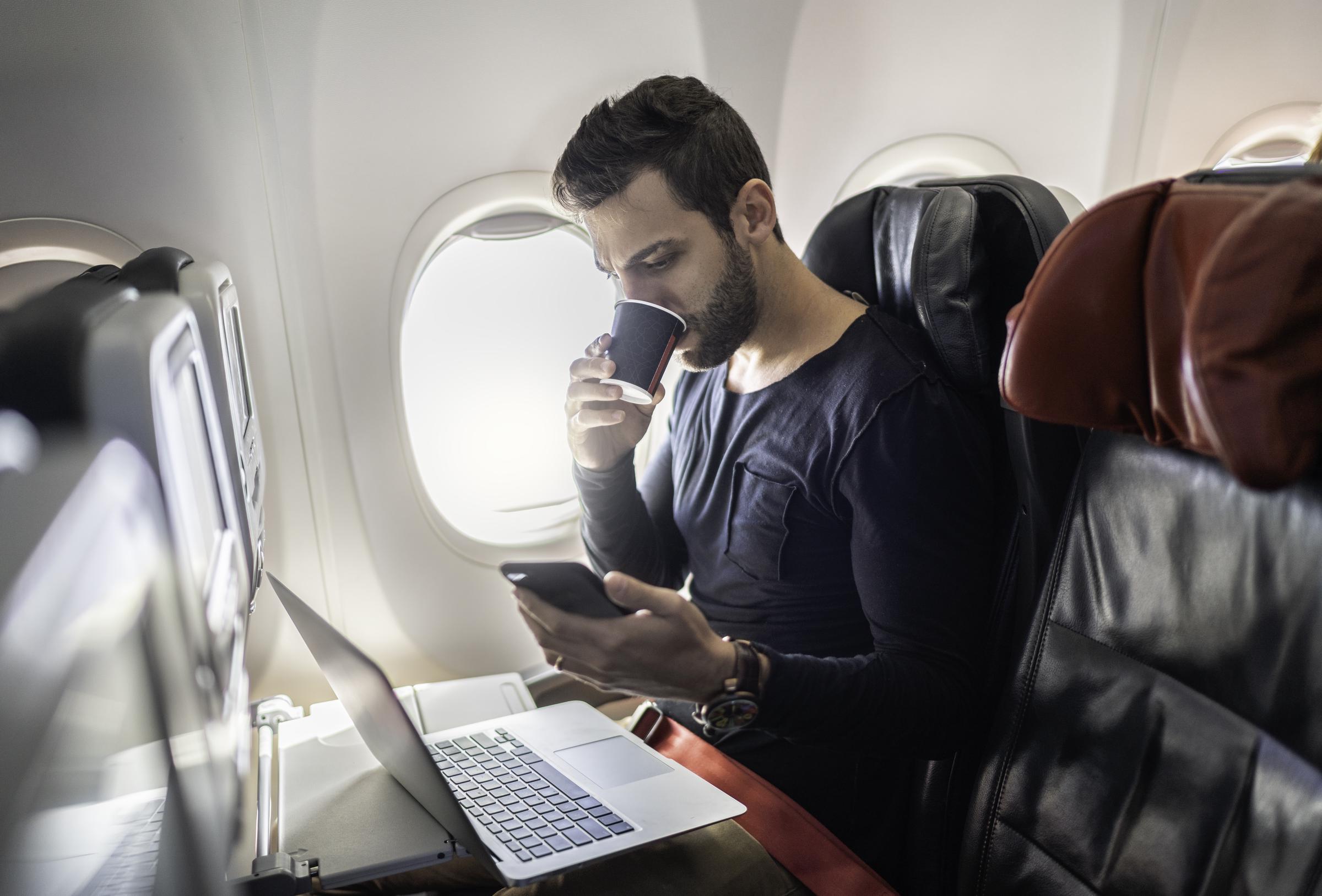 A man drinking coffee while working during a flight | Source: Getty Images