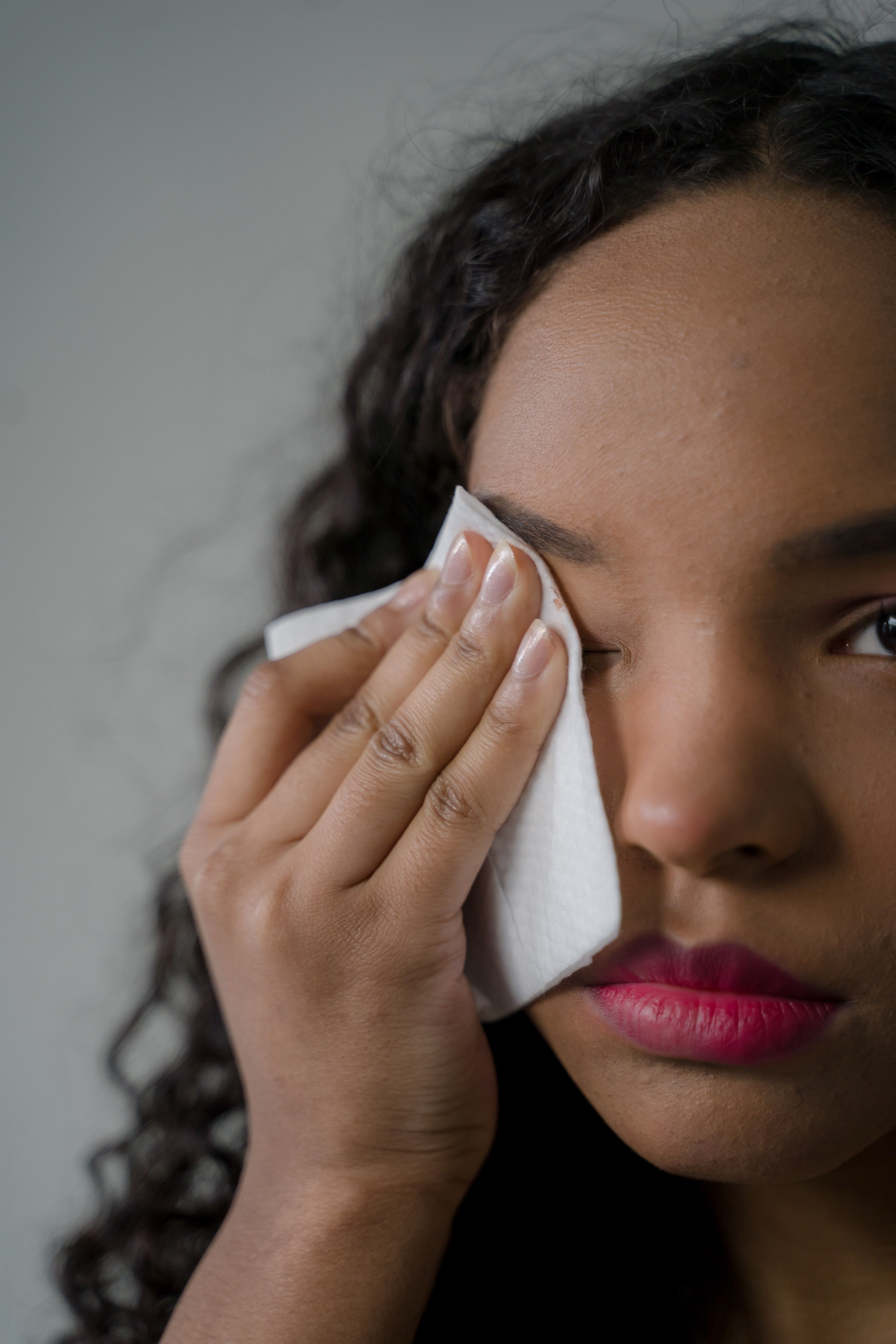 Woman rubbing her eye with makeup wipes | Source: Pexels
