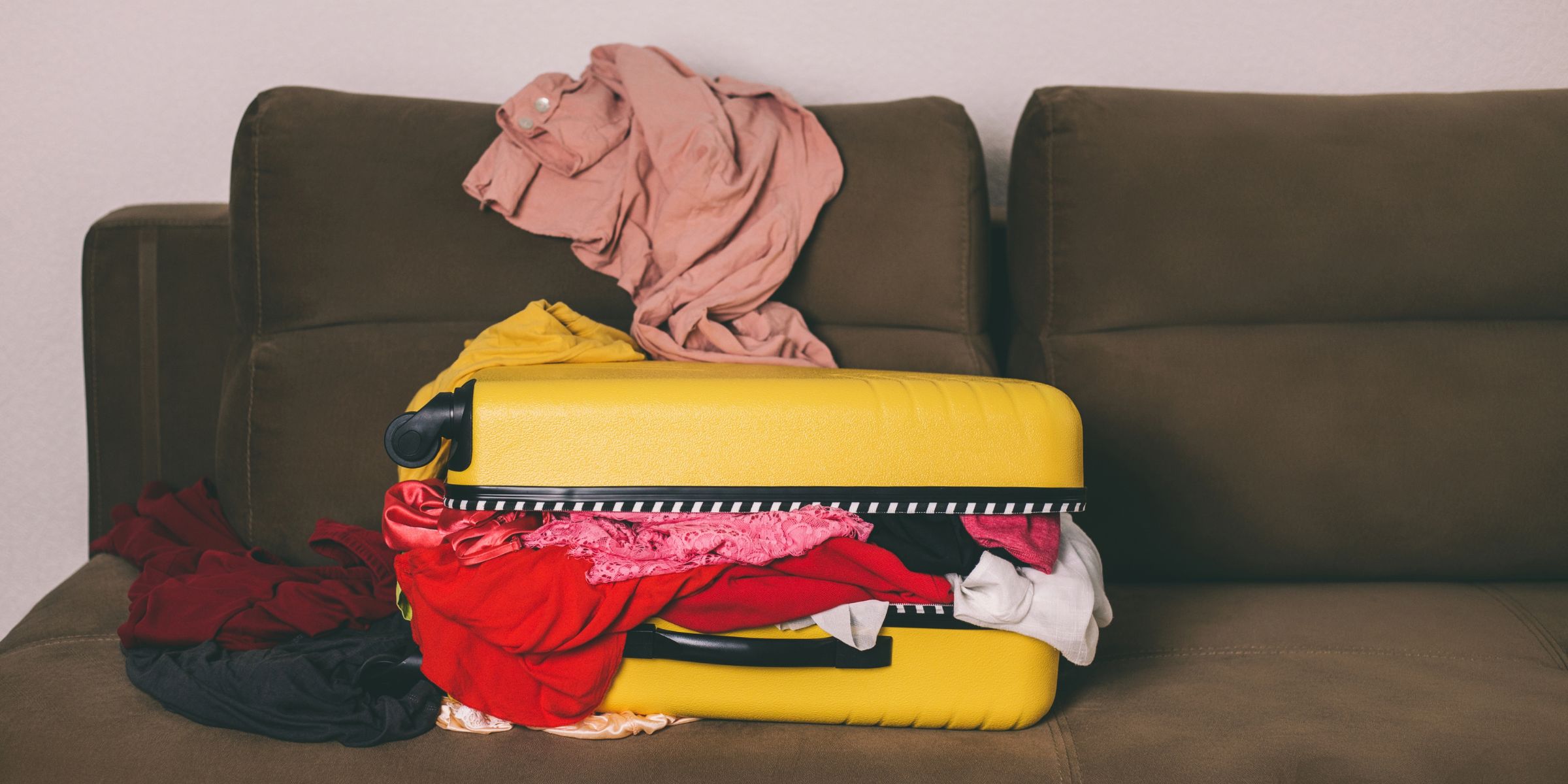 An unzipped suitcases overflowing with clothes | Source: Getty Images