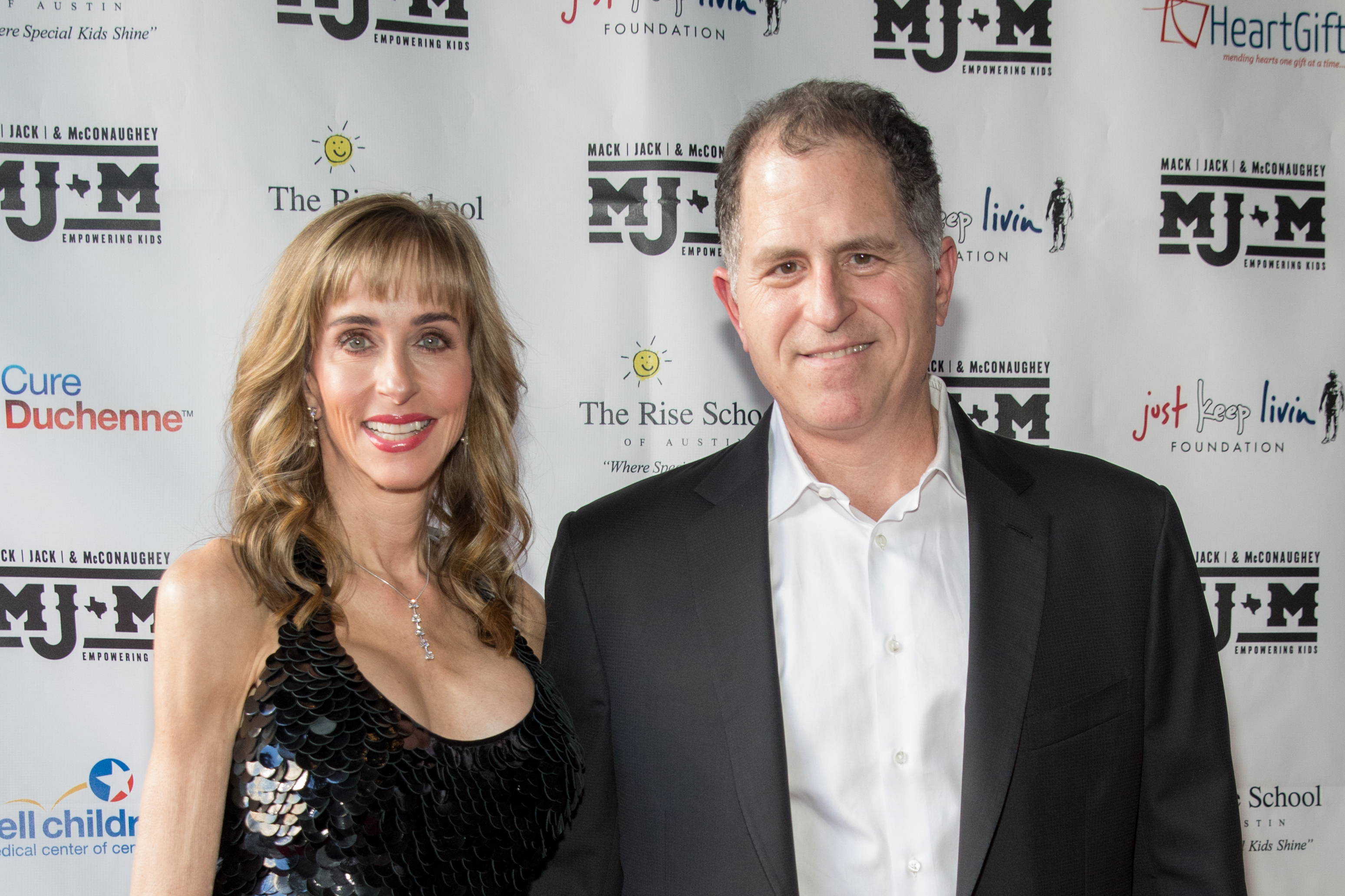 Philanthropists Susan and Michael Dell smiled side by side on the red carpet while arriving at the Mack, Jack & McConaughey charity gala at ACL Live on April 25, 2019, in Austin, Texas. Susan wore a black sequined halter-style evening gown accented with a dangling diamond pendant necklace and earrings, while Michael coordinated in a classic black blazer over an open-collar white dress shirt. | Source: Getty Images