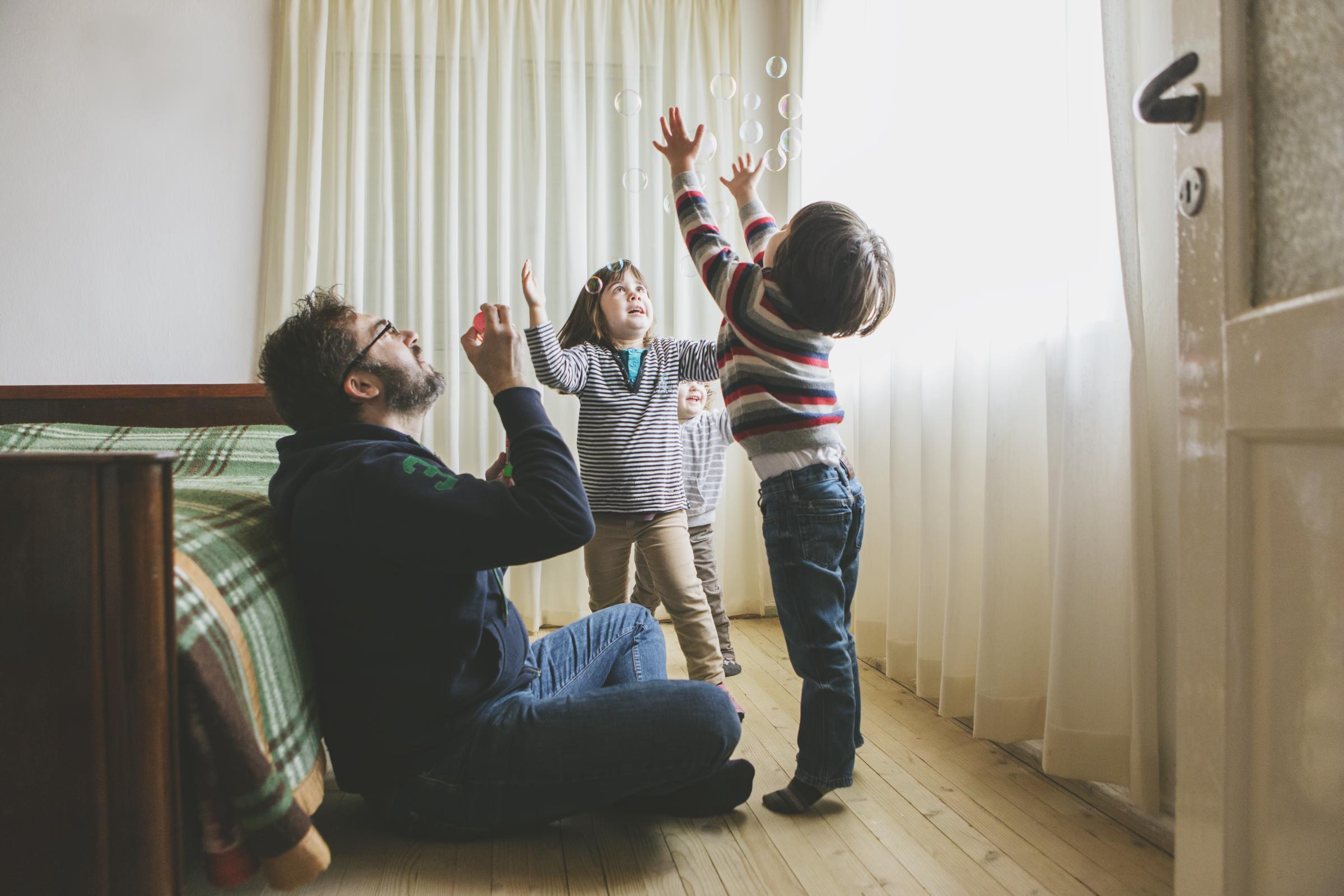A dad blowing bubbles for his kids | Source: Getty Images