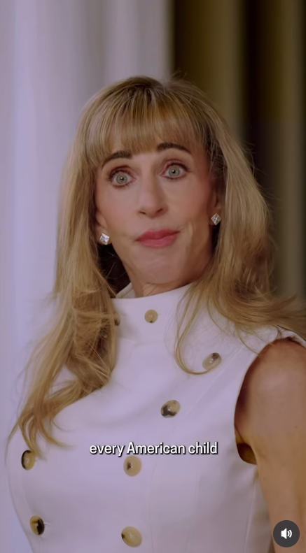 Susan Dell delivers a message in a promotional video discussing youth investment initiatives. She wears a high-collared, double-breasted white sleeveless dress detailed with horn-style buttons, accented with sparkling diamond stud earrings while sporting her blonde-highlighted hair in soft waves with fringe bangs. | Source: Instagram/michaeldell