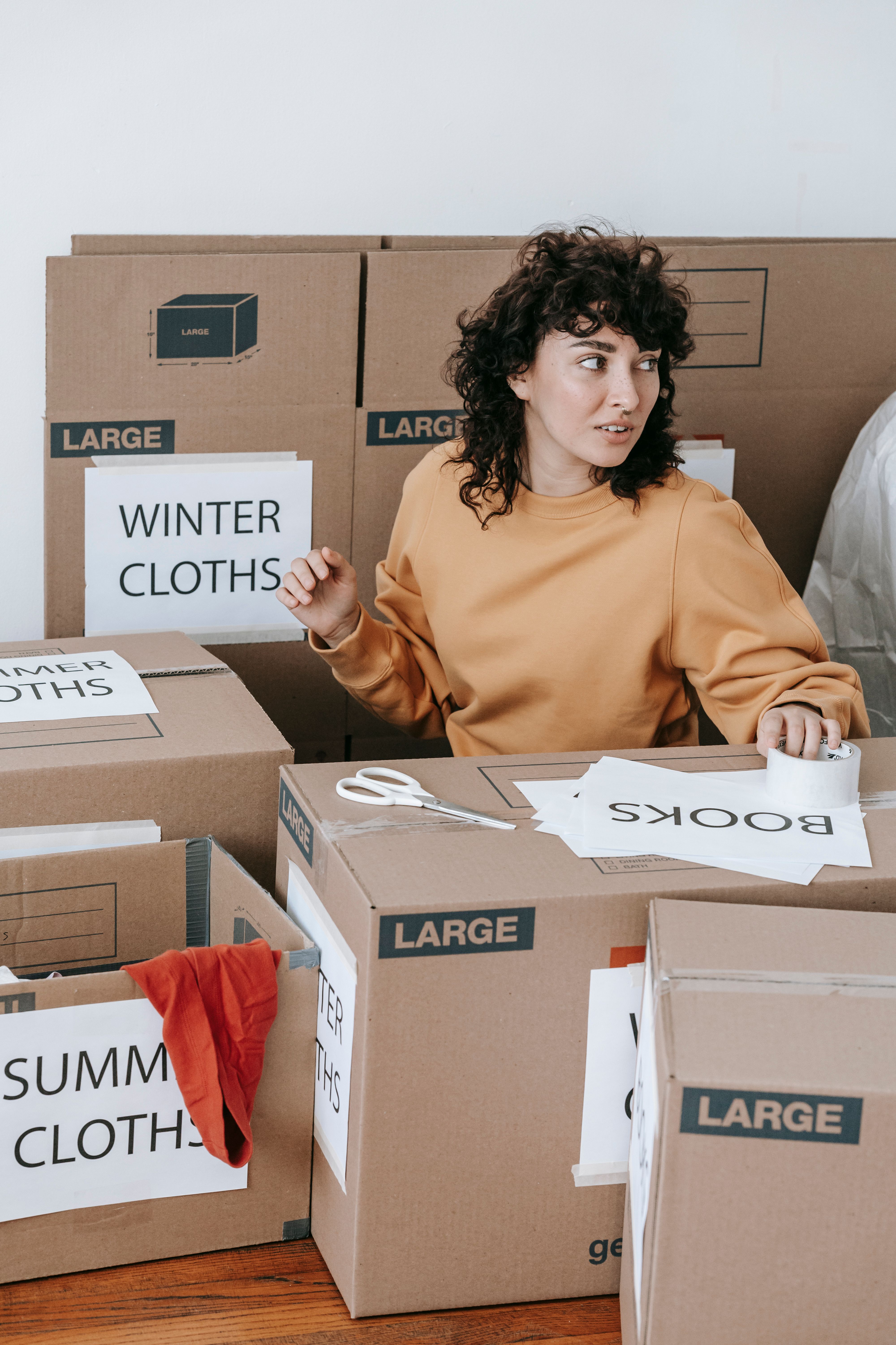 Woman sorting her clothes by category in boxes | Source: Pexels