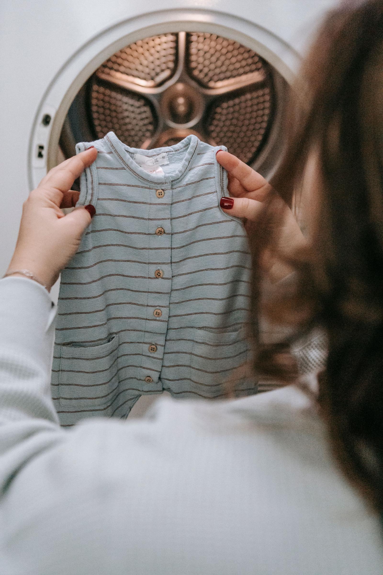 Woman holding up a onesie after washing | Source: Pexels