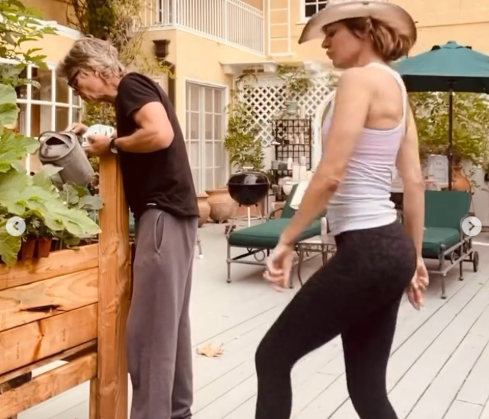 Lisa Rinna and Harry Hamlin appear in a playful outdoor moment, with Hamlin tending to the garden while Rinna gestures animatedly nearby. | Source: Instagram/lisarinna