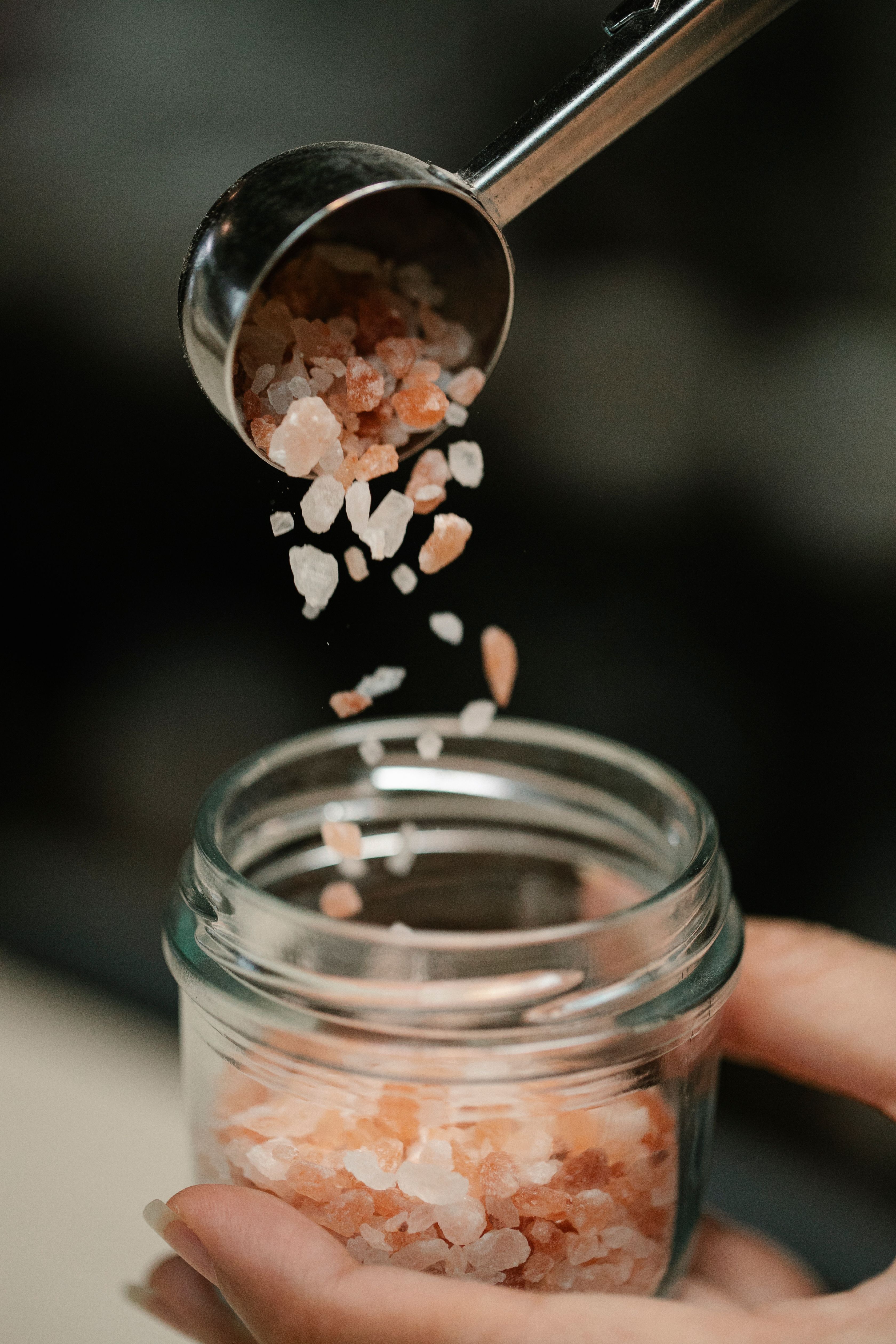 Pink Himalayan salt being poured into a glass jar | Source: Pexels