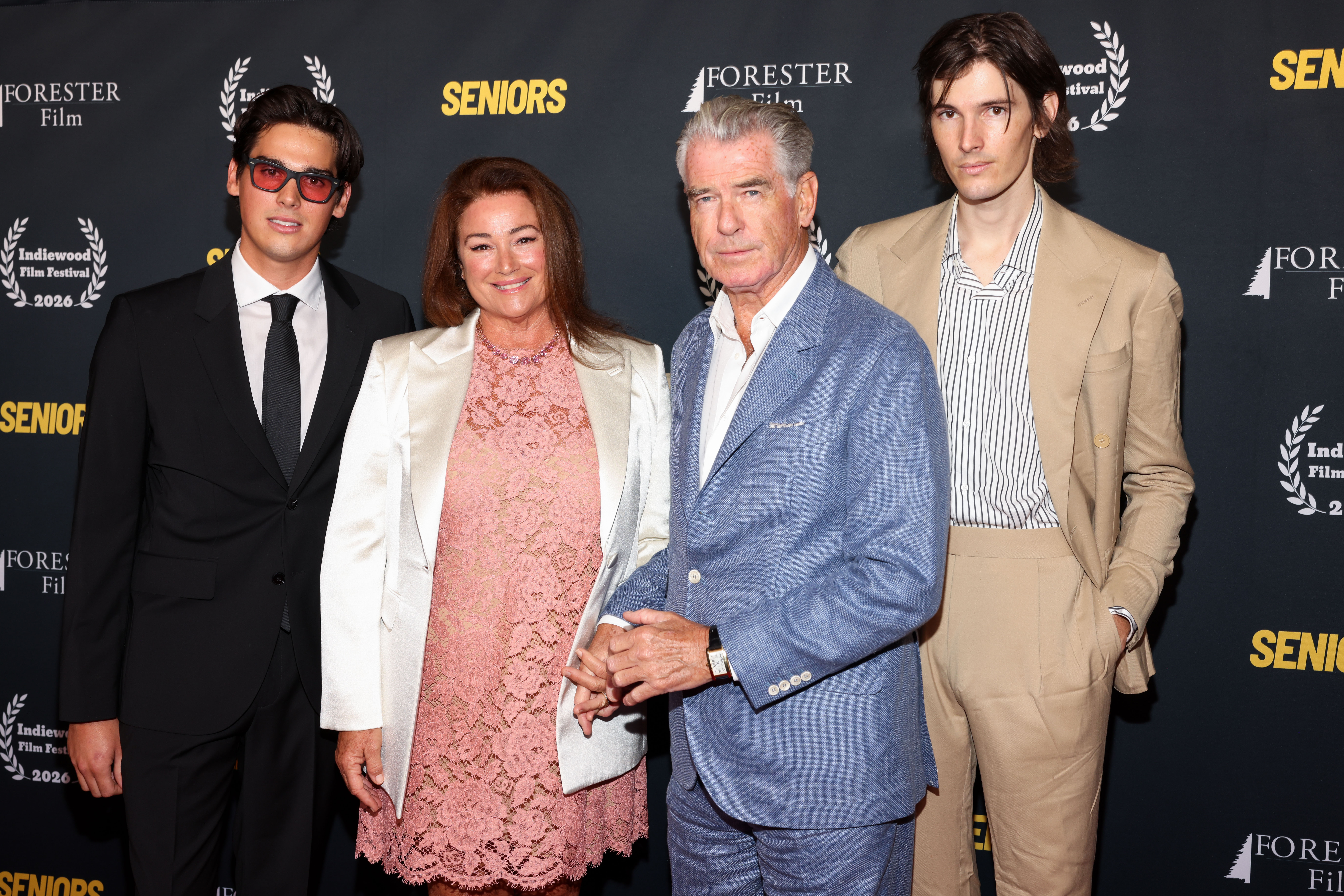Paris, Keely Shaye Smith, Pierce and Dylan Brosnan posed together at the "Seniors" premiere during the 2026 Indiewood Film Festival. The photograph captures the parents with both of their adult sons, whose contrasting black and tan suits drew attention alongside Pierce's blue ensemble. | Source: Getty Images