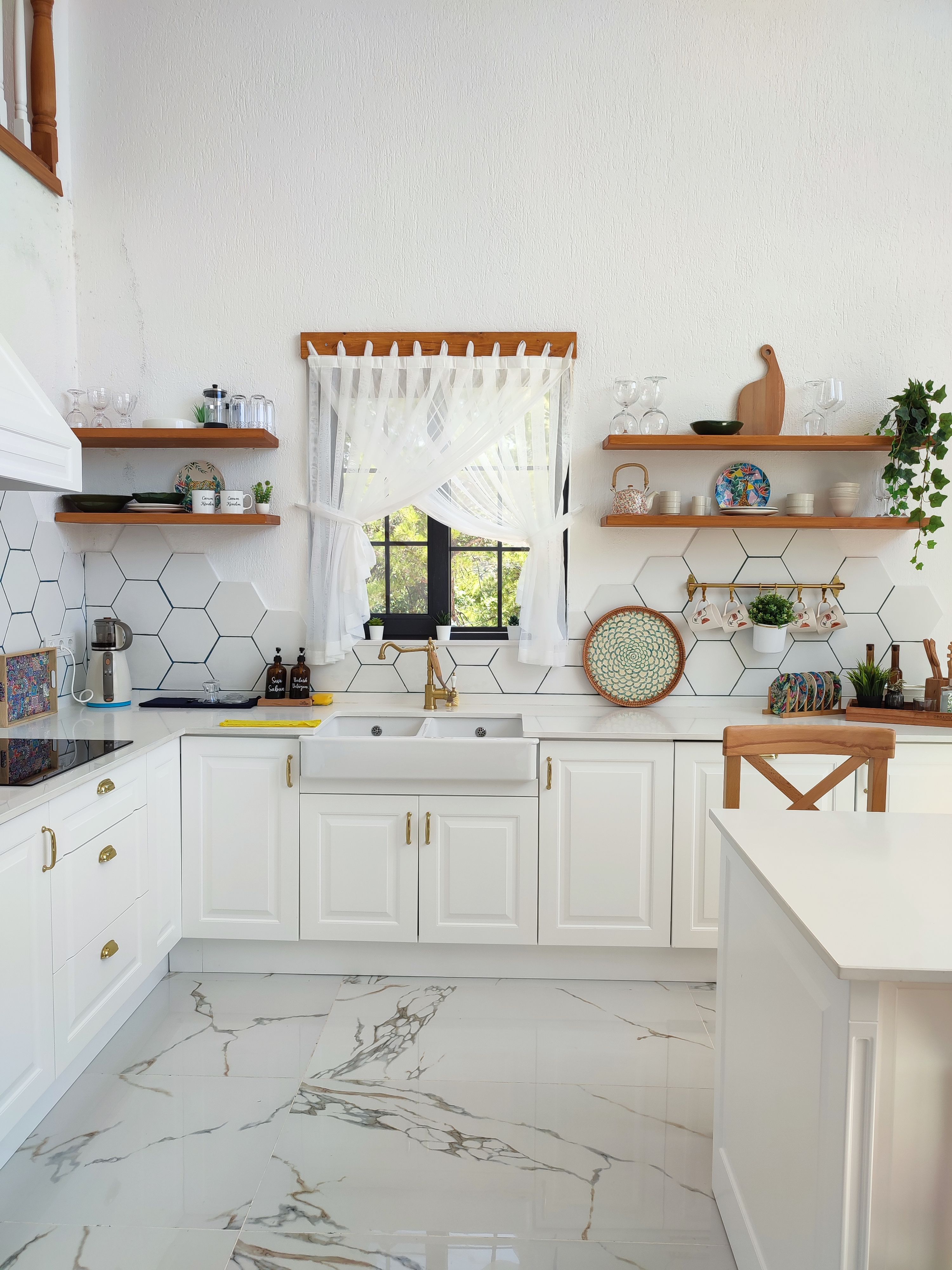 A bright white kitchen features open wooden shelves and a farmhouse sink. | Source: Pexels