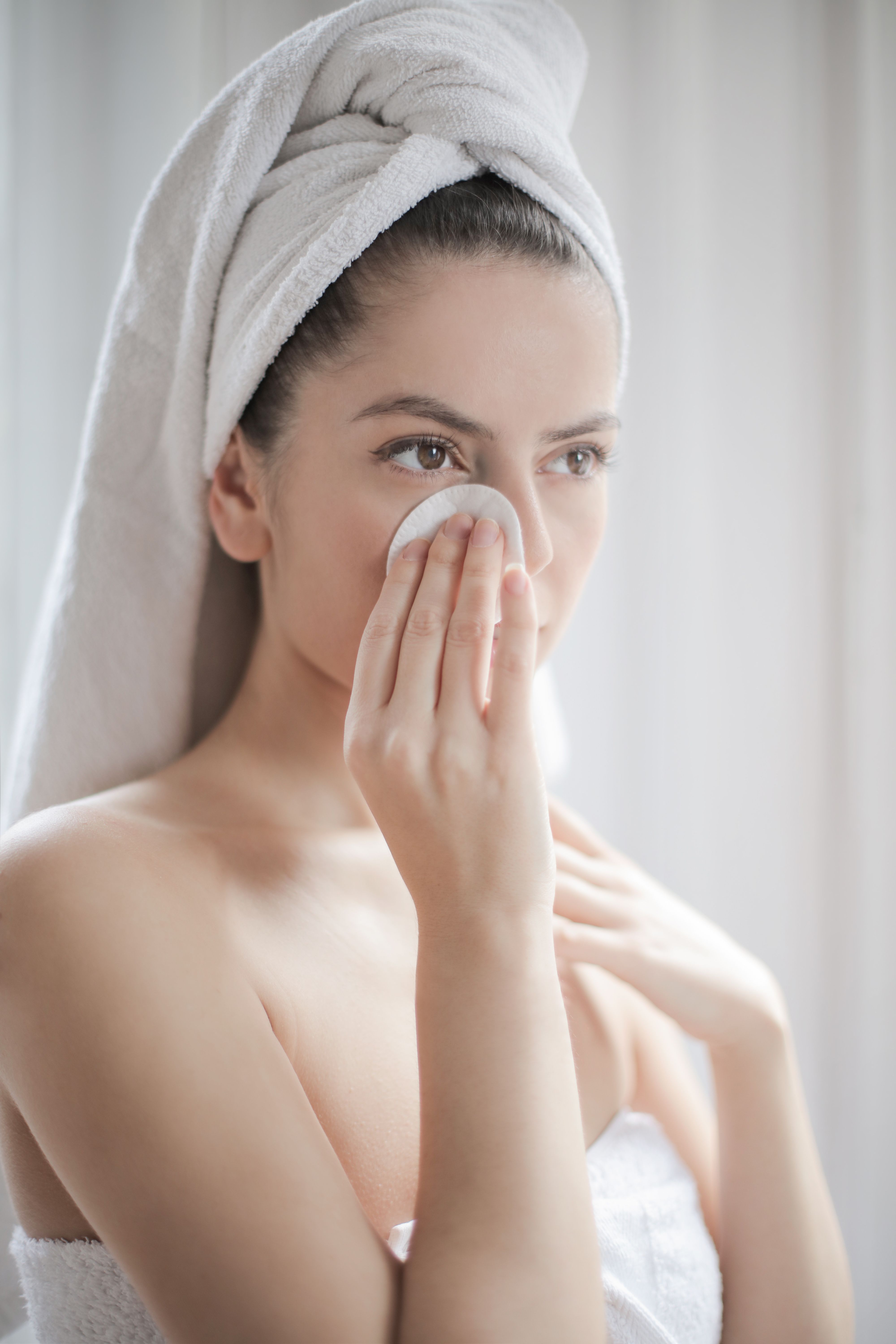Woman using a cotton pad to wipe around her eye | Source: Pexels