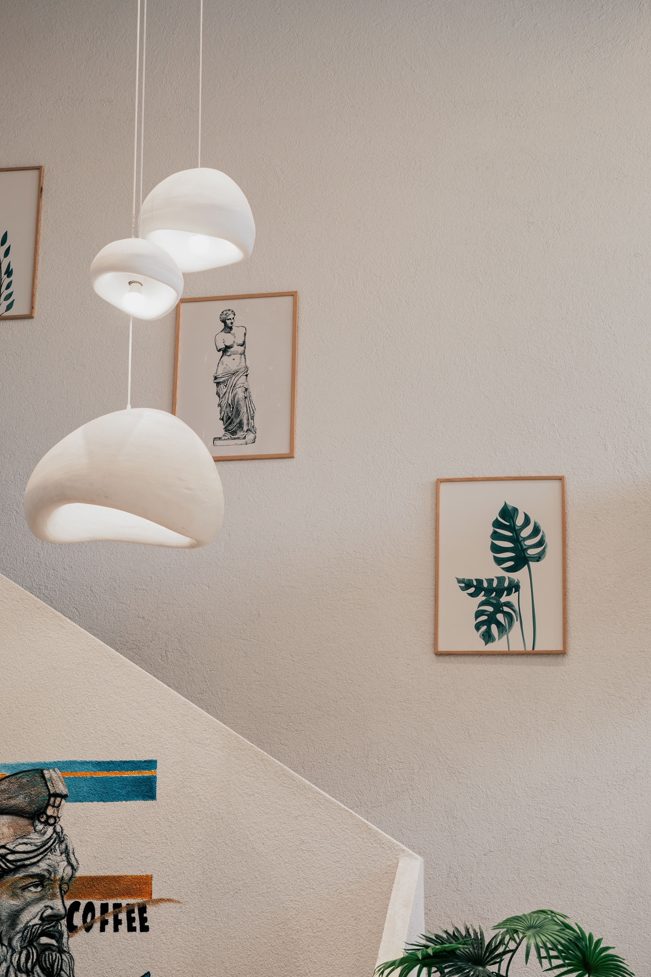 White pendant lights hang beside framed artwork on a textured wall. | Source: Pexels