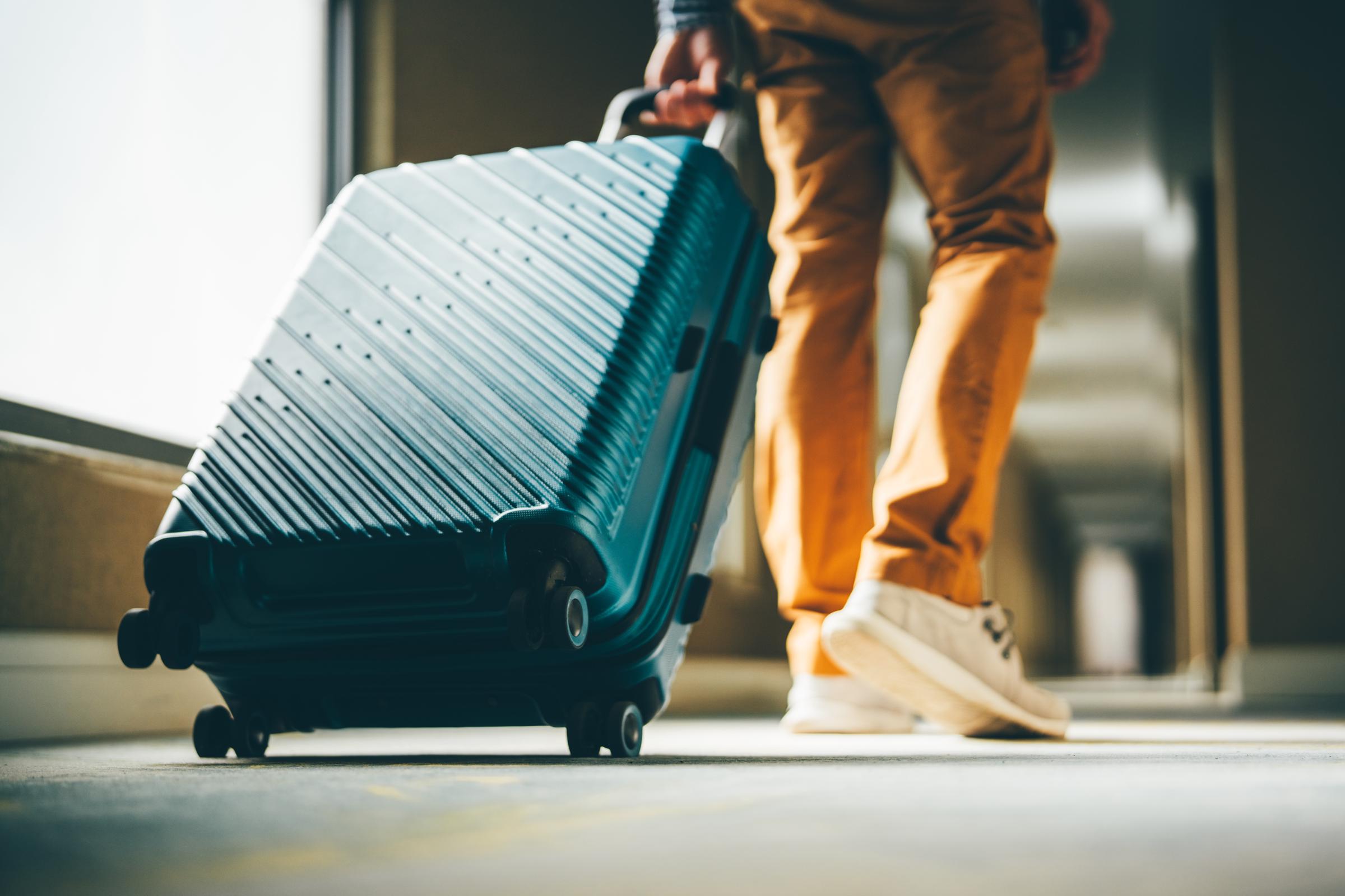 A man walks down a hotel corridor with luggage | Source: Getty Images