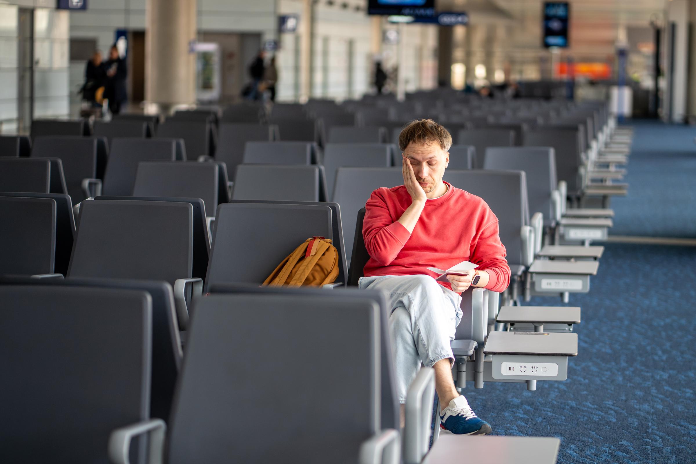 A sleepy traveler checks his boarding pass during layover | Source: Getty Images