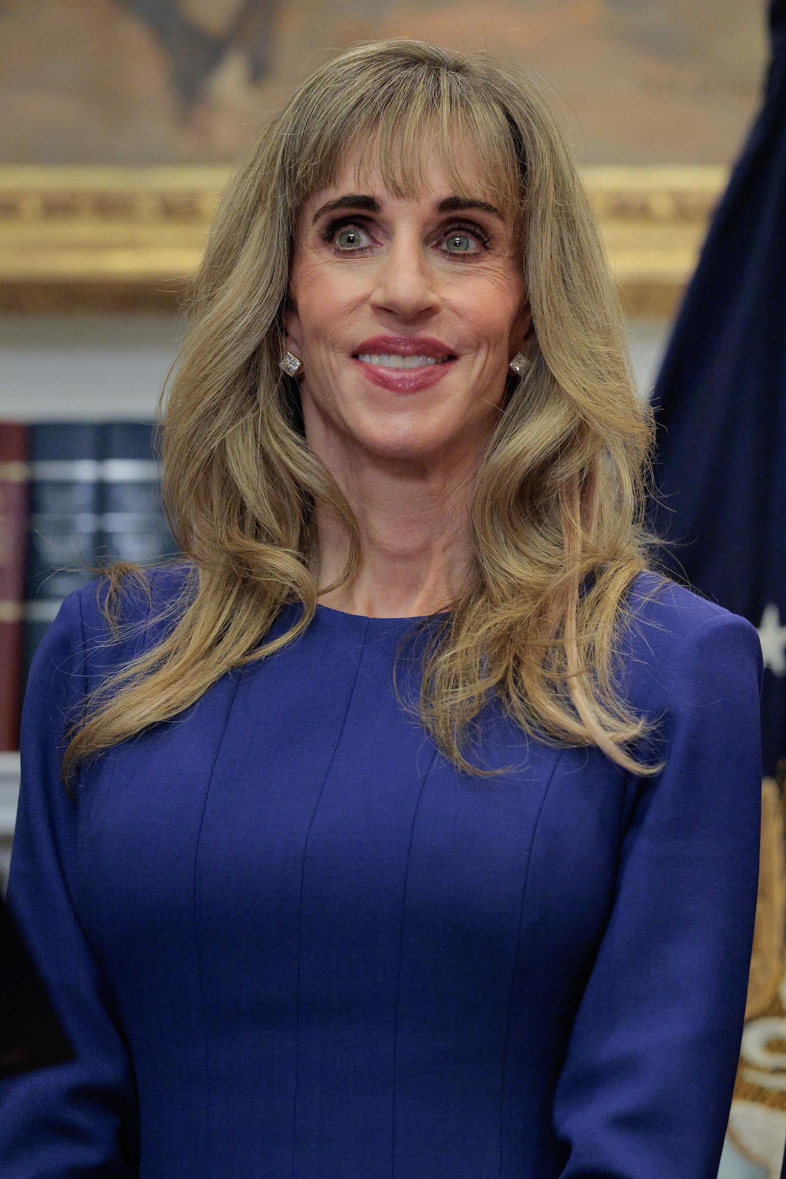 Susan Dell, tech philanthropist and wife of Michael Dell, smiles in the Roosevelt Room at the White House on December 2, 2025, in Washington, D.C. She attended the announcement of a $6.25 billion contribution toward the "Trump accounts" youth investment initiative, wearing a structured royal blue dress, diamond stud earrings, and her hair styled in soft waves with fringe bangs. | Source: Getty Images