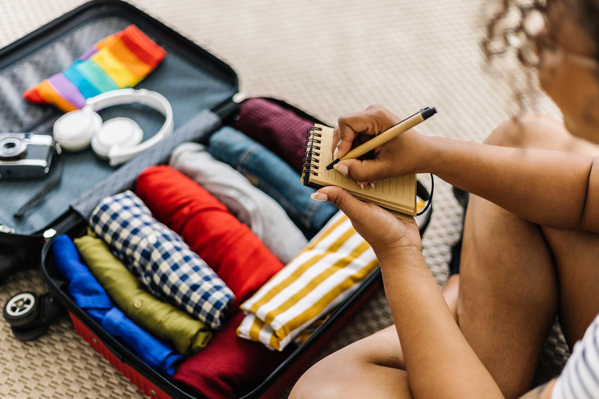 A woman writing a list of accessories and travel stuff before going on summer holiday | Source: Getty Images