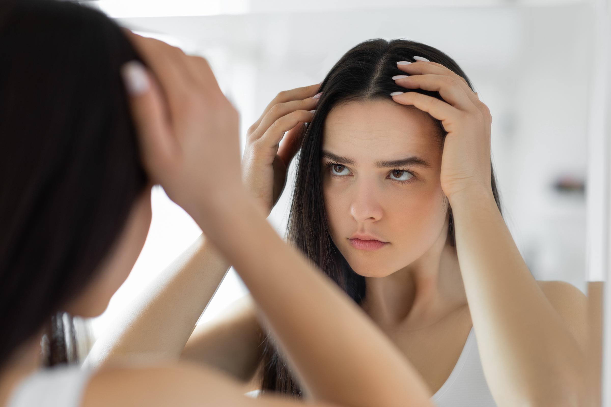 A young woman inspecting her scalp | Source: Getty Images